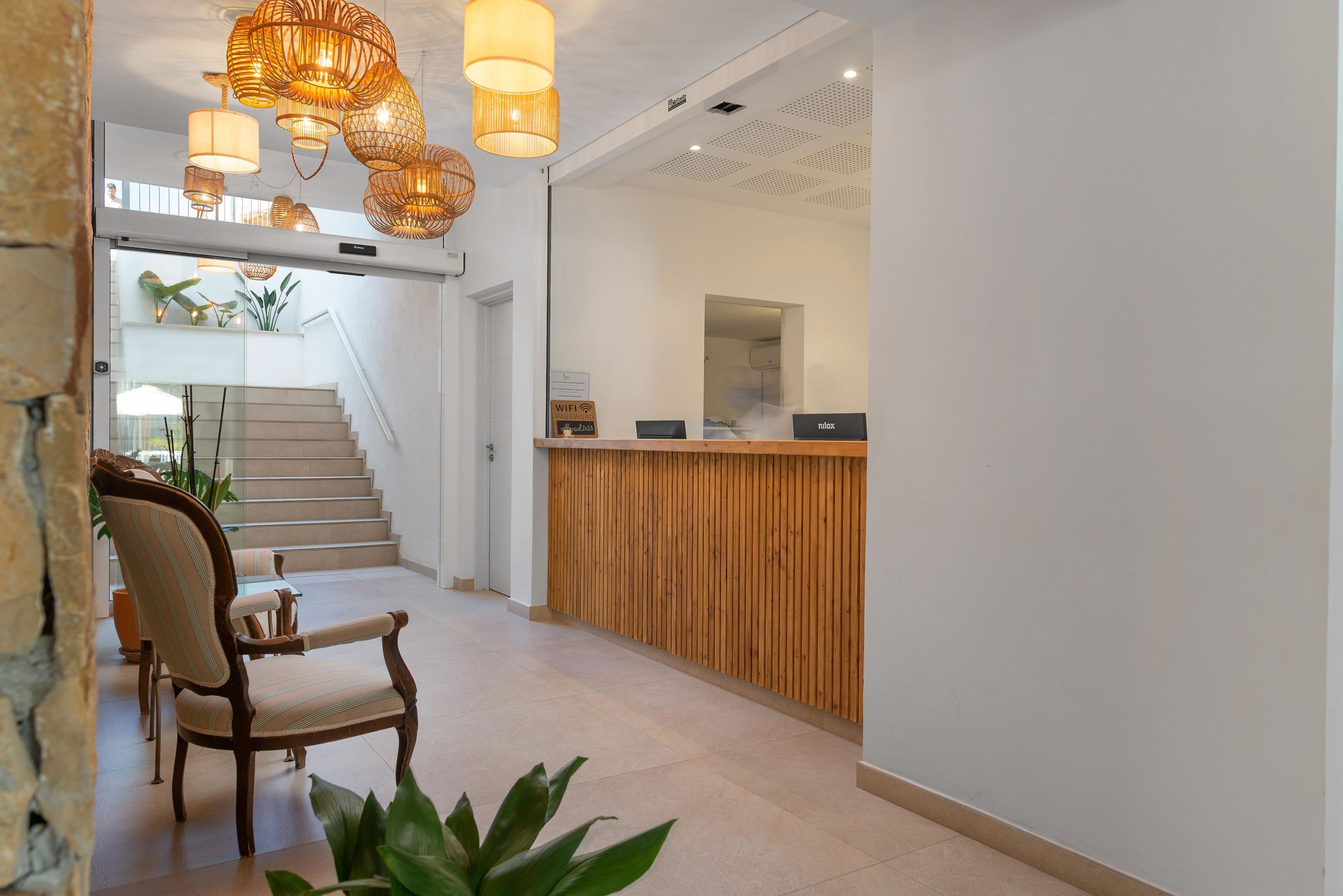 A reception area with a wooden desk, a chair, and a staircase leading to an upper level.