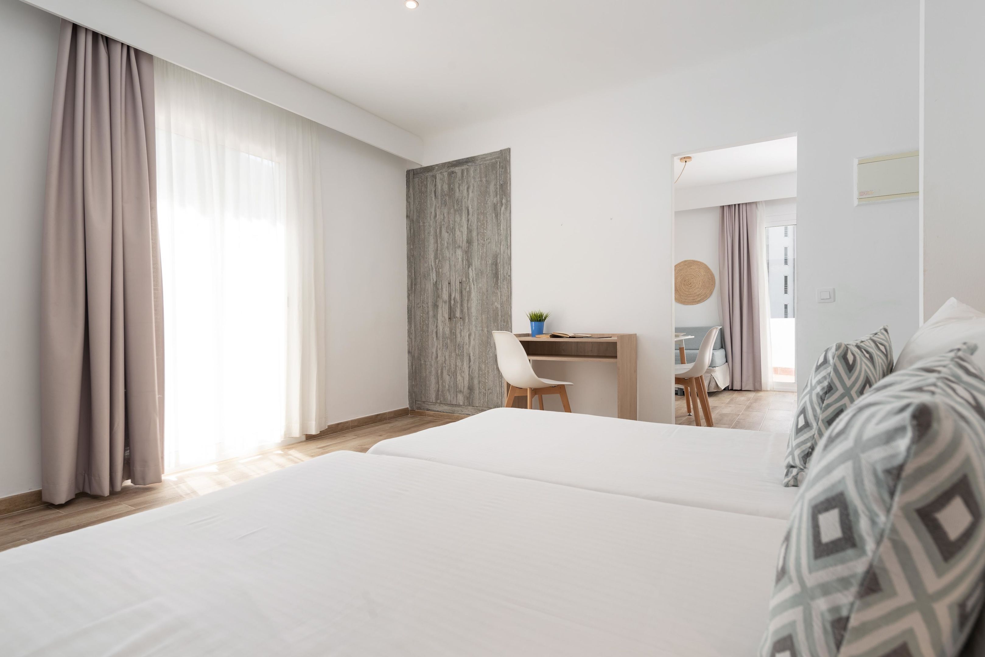 A modern hotel room with a large bed, a desk, and a chair.