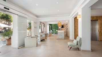 Un hall d’hôtel spacieux au design moderne, comprenant un coin salon, un comptoir d’accueil et une vue sur l’espace extérieur.