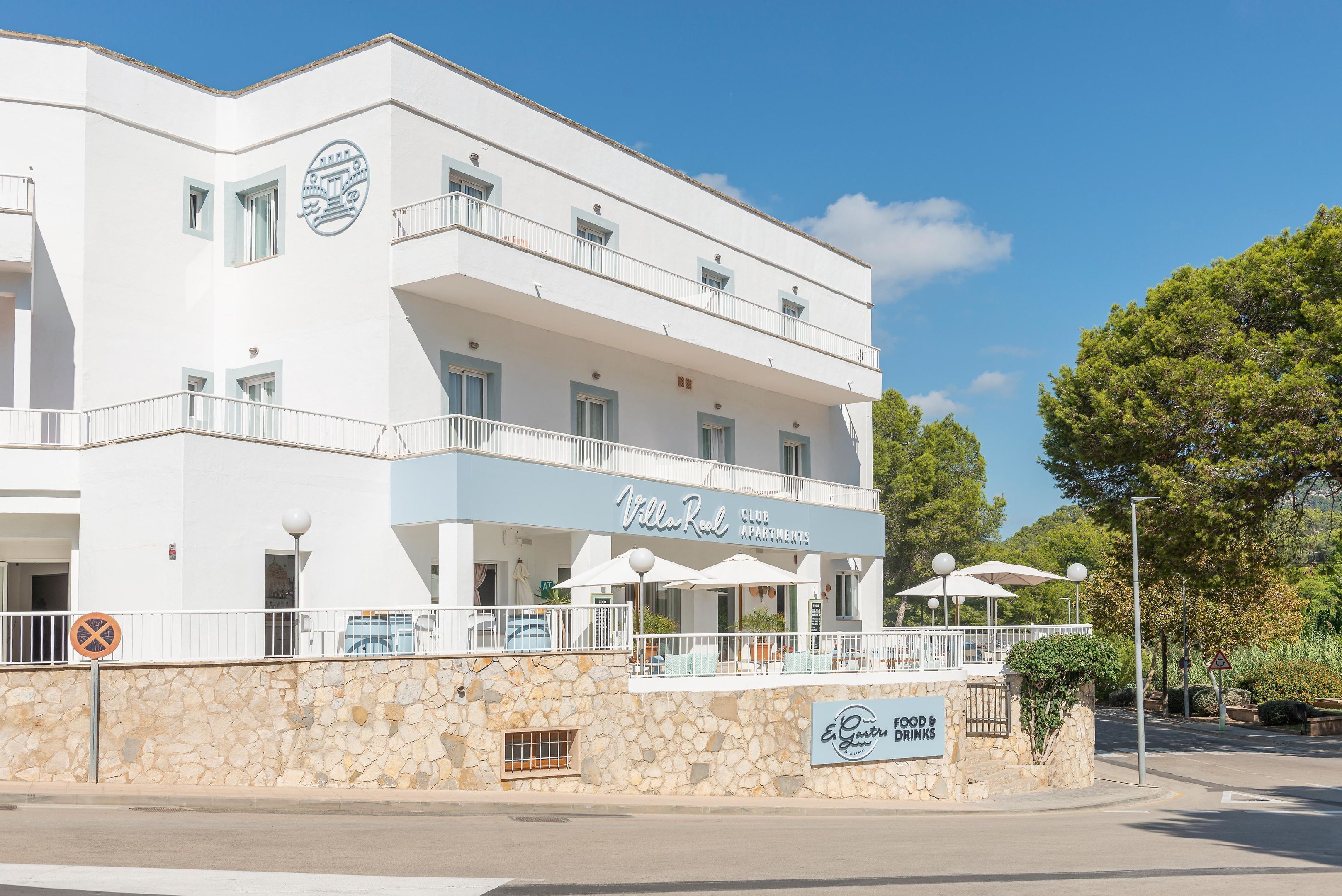 Un edificio blanco con balcones y un letrero que dice "Villa Real Club Apartments".