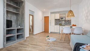 Een modern appartement met een woonkamer, kitchenette en een eethoek.