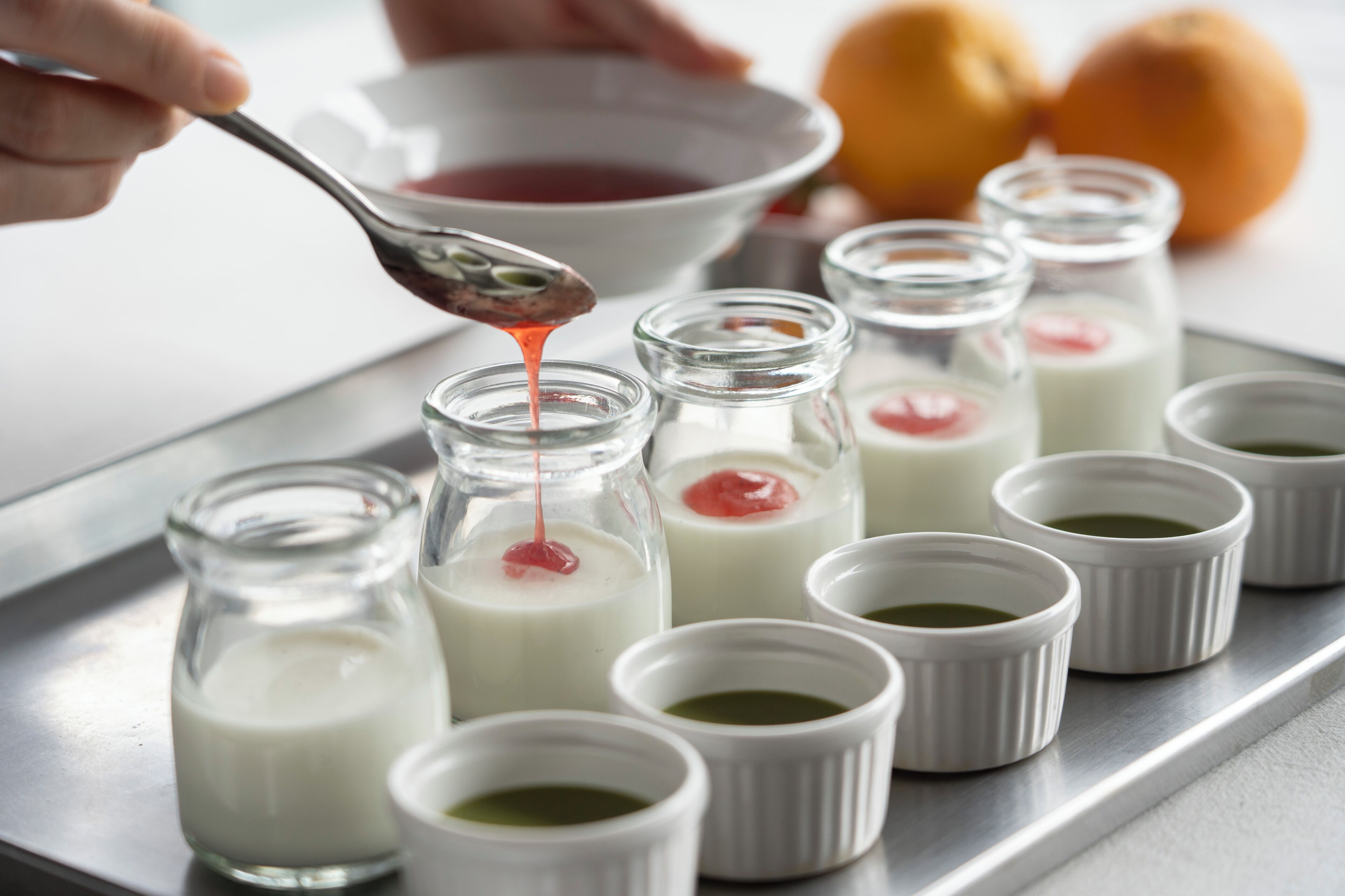 A tray with small glass jars containing a white liquid, some with a red substance on top.