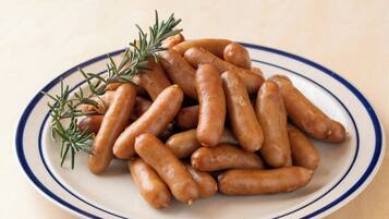 A plate of sausages with rosemary garnish.