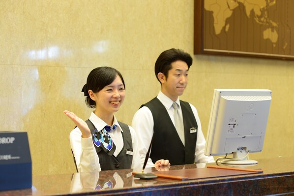 A reception desk with a computer monitor, a nameplate, and a sign that reads "DROP".