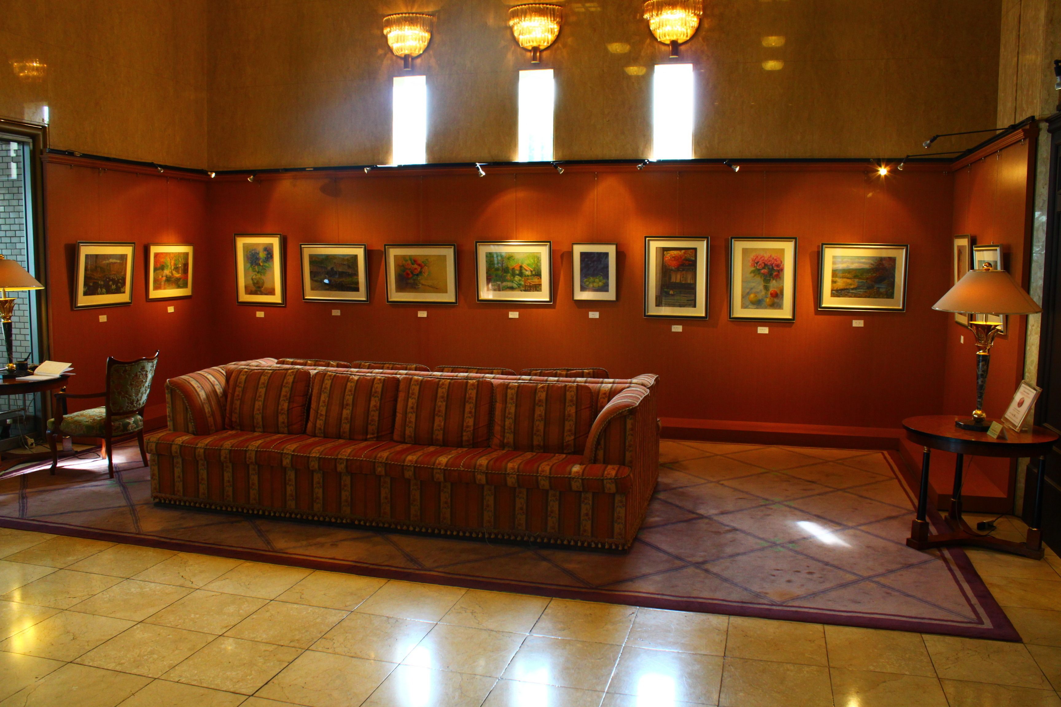 Um hall com sofá, obras de arte emolduradas na parede e um candelabro.
