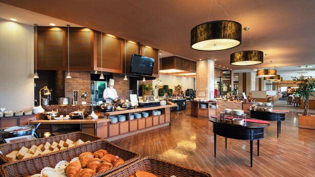 Een modern ontbijtbuffet met diverse gerechten en een kok die aan het koken is.