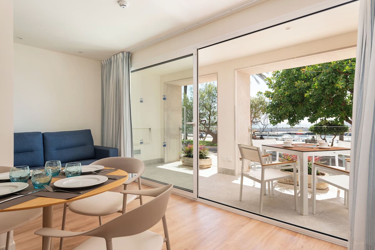 A modern room with a dining area, a sofa, and a view of the outdoors.