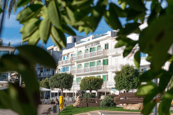 Un hotel con balcones, mobiliario exterior y vegetación.