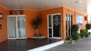 Een motel ingang met een receptiebalie, glazen deuren en een bord met openingstijden.
