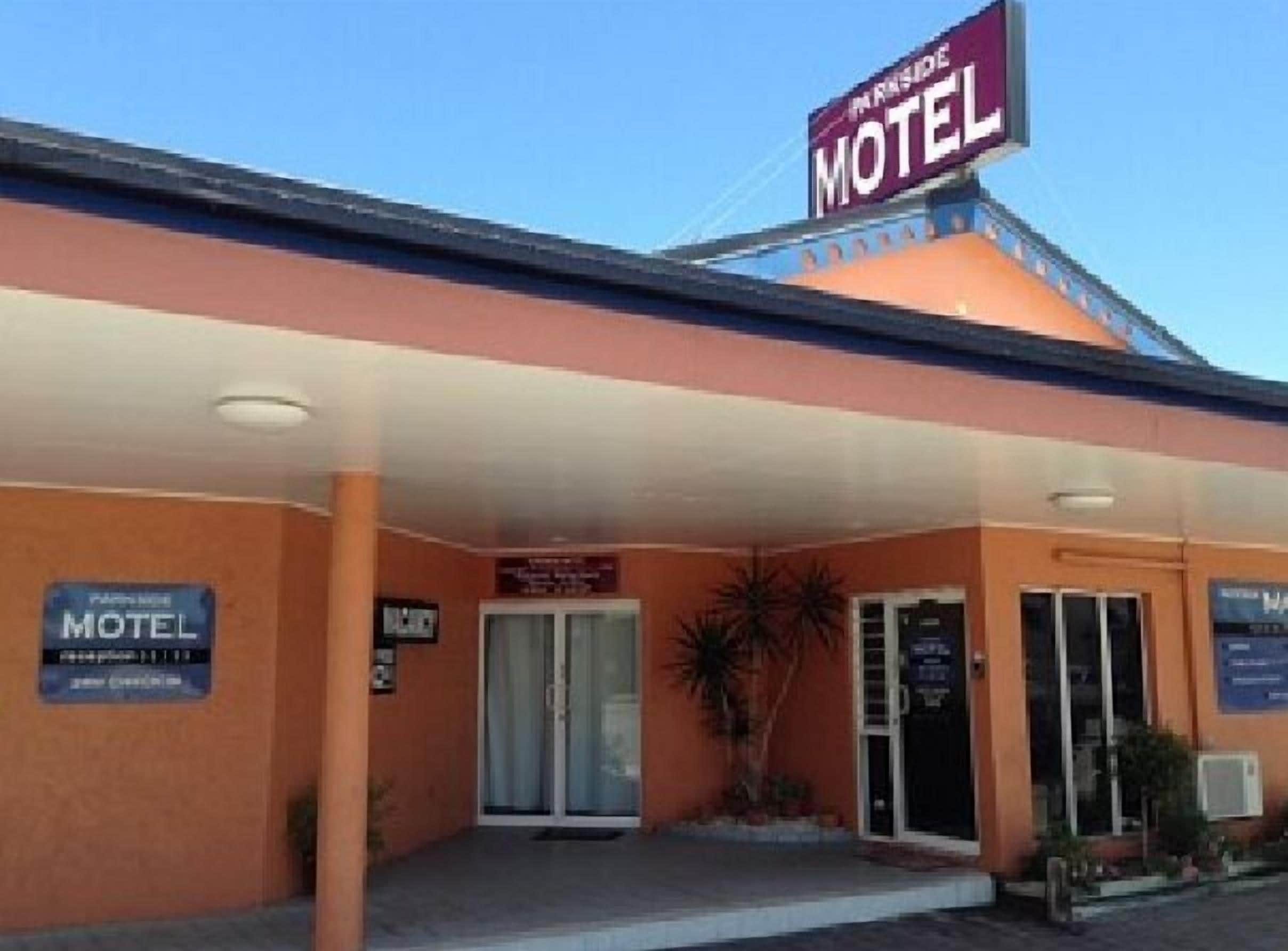 Un motel avec une enseigne bien visible, une entrée abritée et un panneau indiquant la disponibilité de places de stationnement.