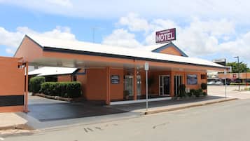 Standalone motel with a flat roof and covered parking area, featuring a main entrance via a covered walkway.