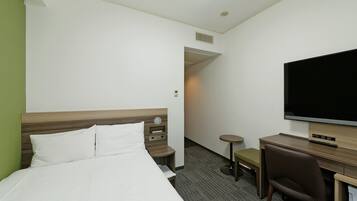 Ein Hotelzimmer mit einem Bett, einem Schreibtisch mit Stuhl, einem Fernseher und einem kleinen Tisch.