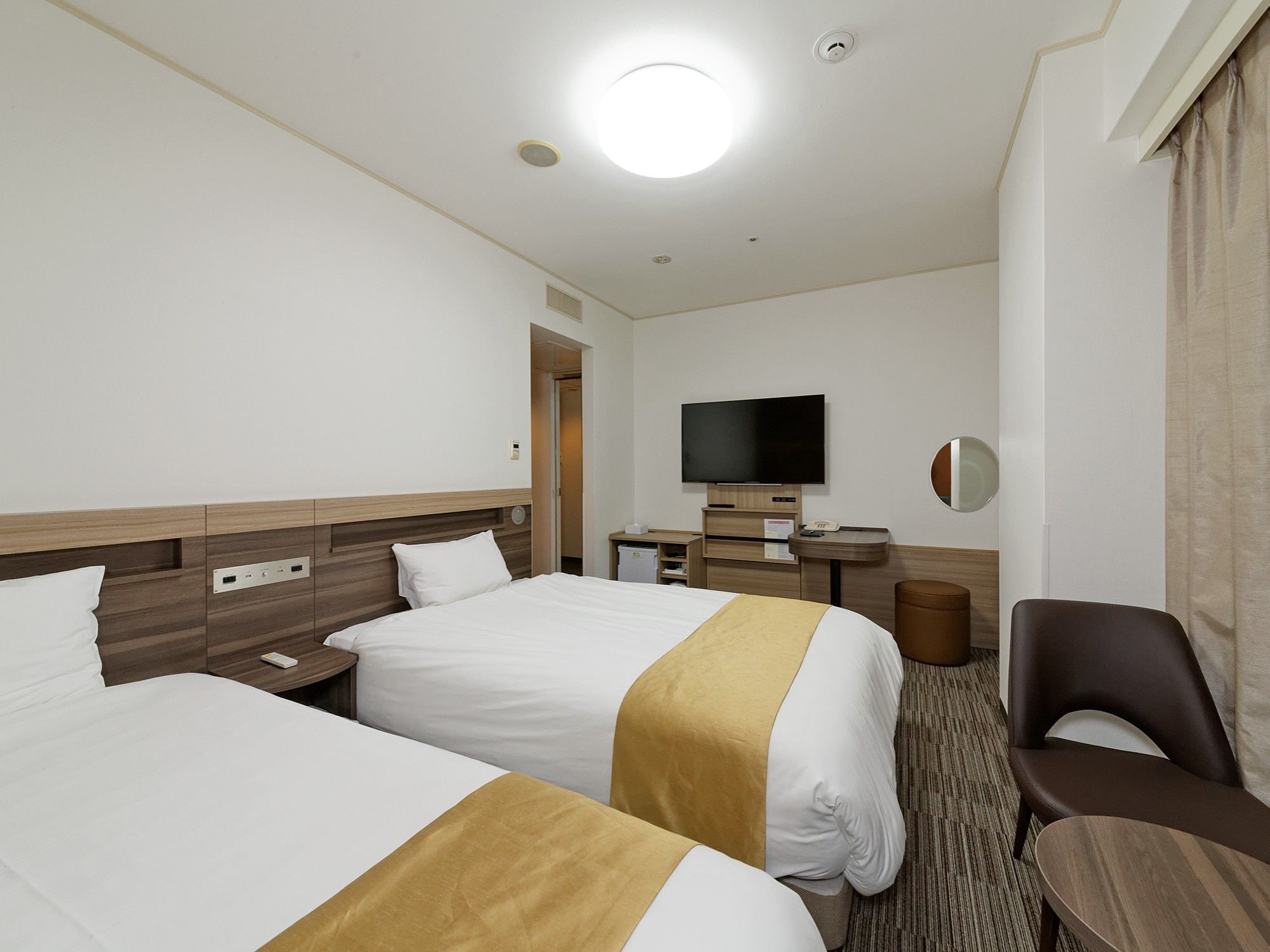 A hotel room with two beds, a television, a desk, and a chair.