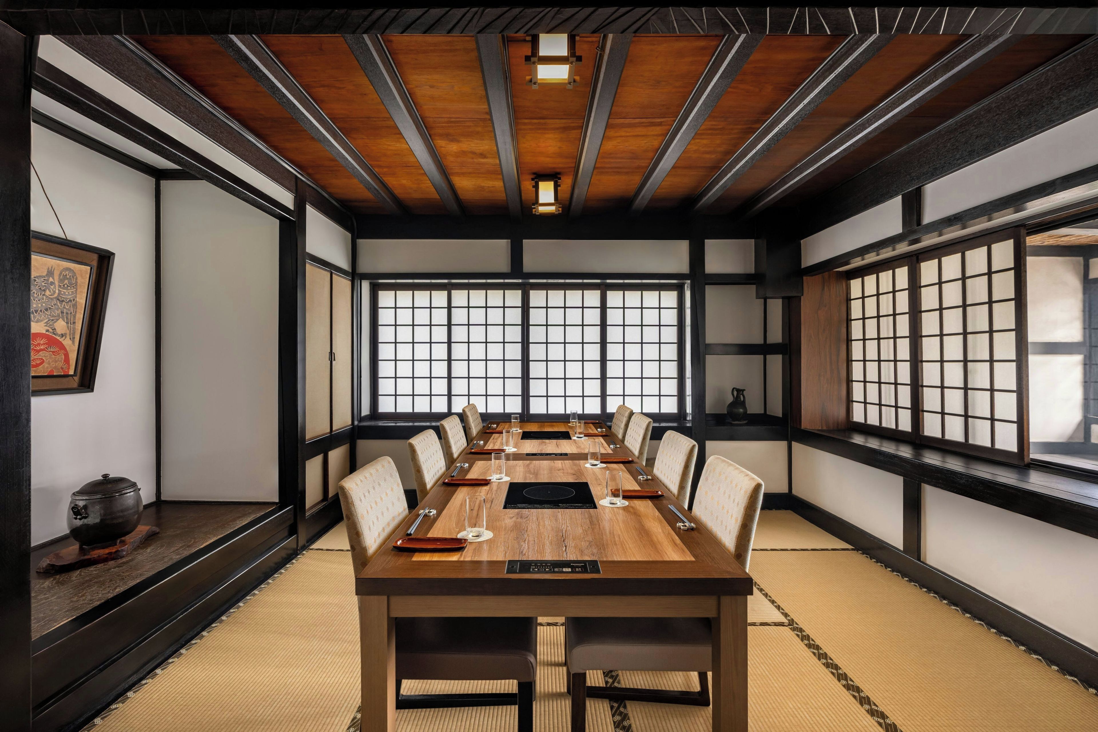 A traditional Japanese-style meeting room with tatami flooring, a long wooden table, and shoji screens.