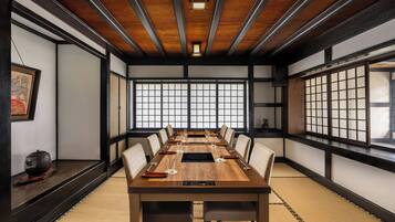 A traditional Japanese-style meeting room with tatami flooring, a long wooden table, and shoji screens.