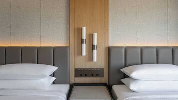 A hotel room with two beds, a wooden panel wall, and a control panel with buttons.