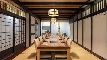 Una sala de reuniones tradicional al estilo japonés, con una larga mesa de madera, suelo de tatami y puertas correderas shoji.