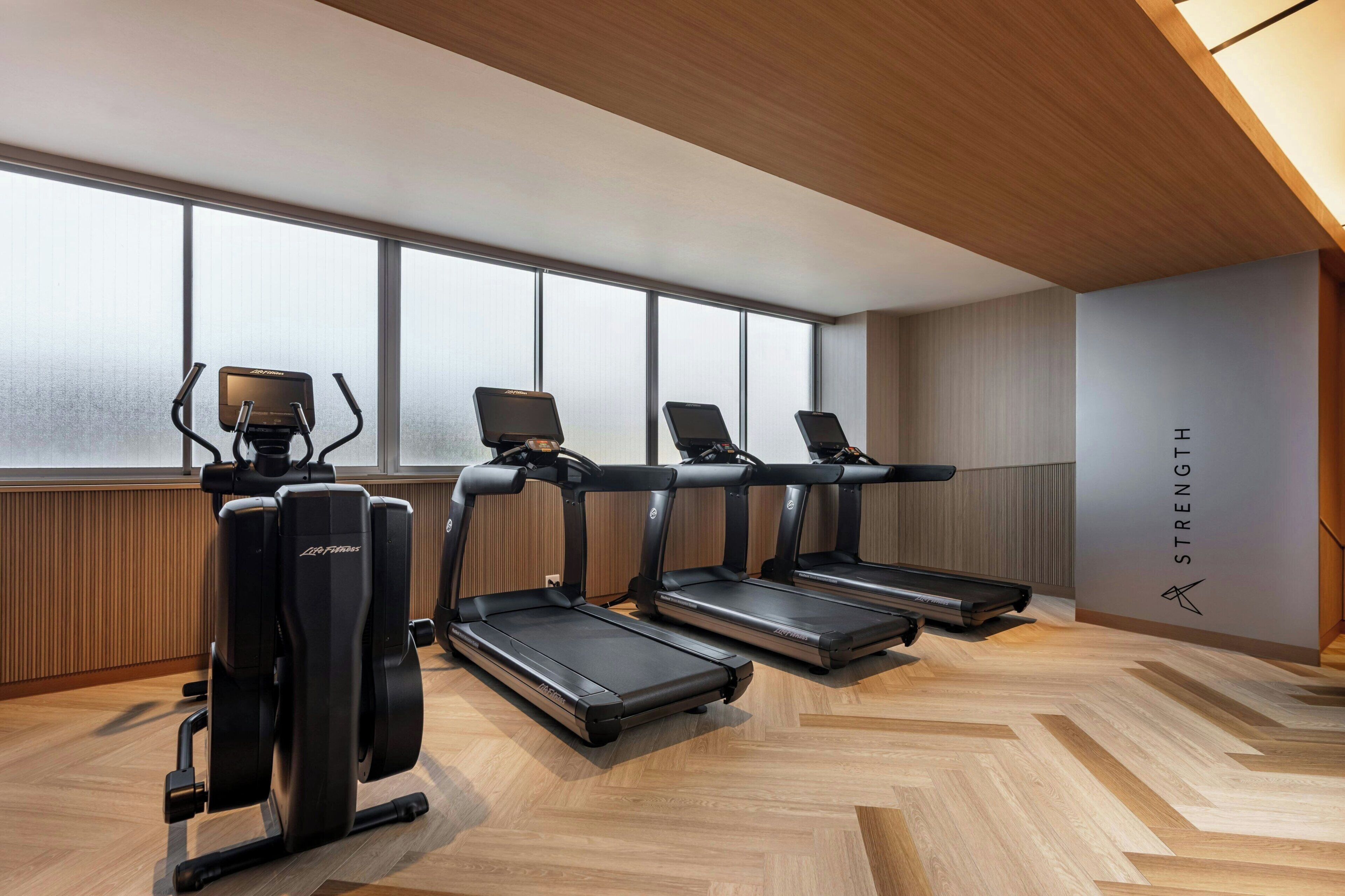 A fitness room with treadmills, a stationary bike, and a rowing machine.