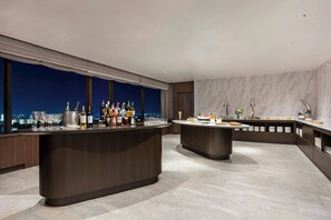 A modern bar area with a city view, a marble wall, and a buffet setup. - Hamamatsu Marriott Hotel (Hamamatsu)