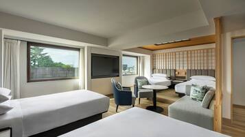 Habitación de hotel con dos camas, un escritorio, una silla y vistas a la ciudad.