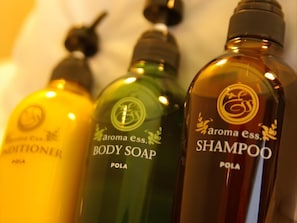 Three bottles of body care products labeled 'aroma ess. BODY SOAP' and 'SHAMPOO' in a row.