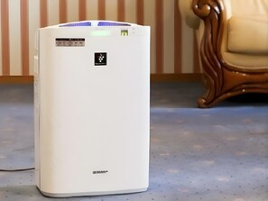 A white air conditioner unit with a digital display and control panel, placed on a blue carpeted floor.