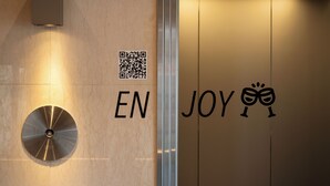 A wall with a QR code, the letters "EN" and "JOY" with a wine glass icon, and a circular metallic object. - EN HOTEL Hamamatsu (Hamamatsu)