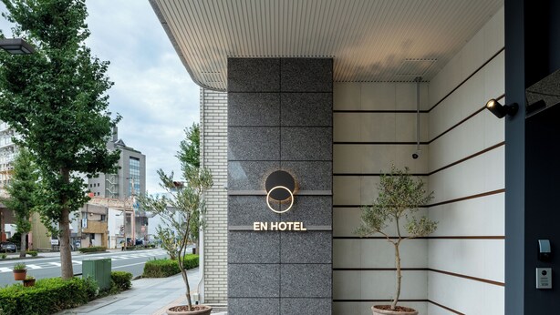A modern hotel entrance with a prominent 'EN HOTEL' sign, a wooden deck, and potted plants. - EN HOTEL Hamamatsu (Hamamatsu)