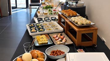 Disposição de buffet com diversos alimentos e um espaço para bebidas.