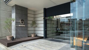 The exterior of a hotel with a modern design, featuring a glass entrance, a potted tree, and a sign that reads "EN HOTEL". - EN HOTEL Hamamatsu (Hamamatsu)