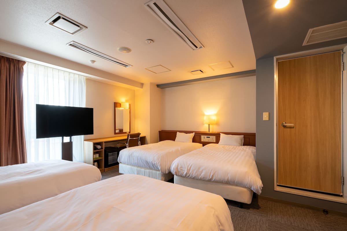 A hotel room with two beds, a desk, a TV, and a wardrobe.