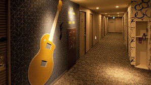 A hotel corridor with geometric patterned walls, a large guitar decoration, and doors numbered 810-818. - EN HOTEL Hamamatsu (Hamamatsu)