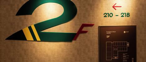 A hotel room number 2F with directional arrows indicating room numbers 201-209 and 210-218.