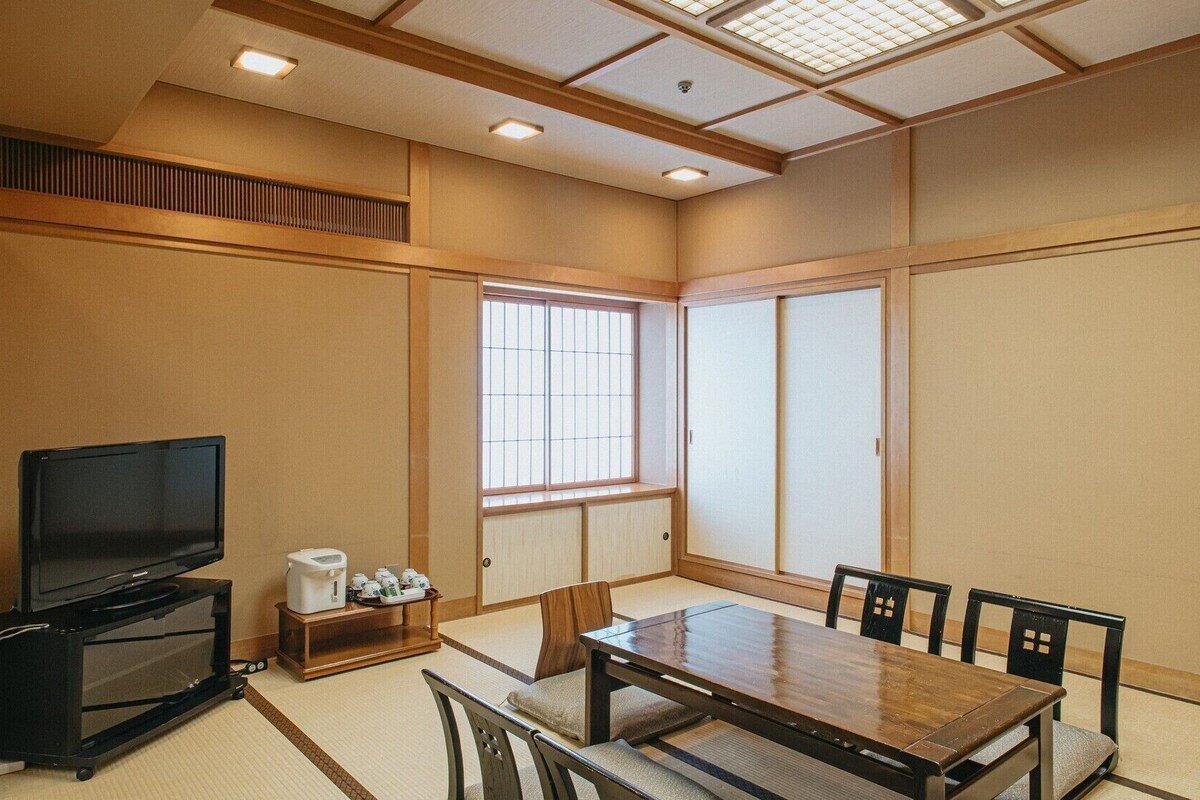 Una habitación de estilo japonés tradicional con suelo de tatami, una mesita baja y puertas correderas.