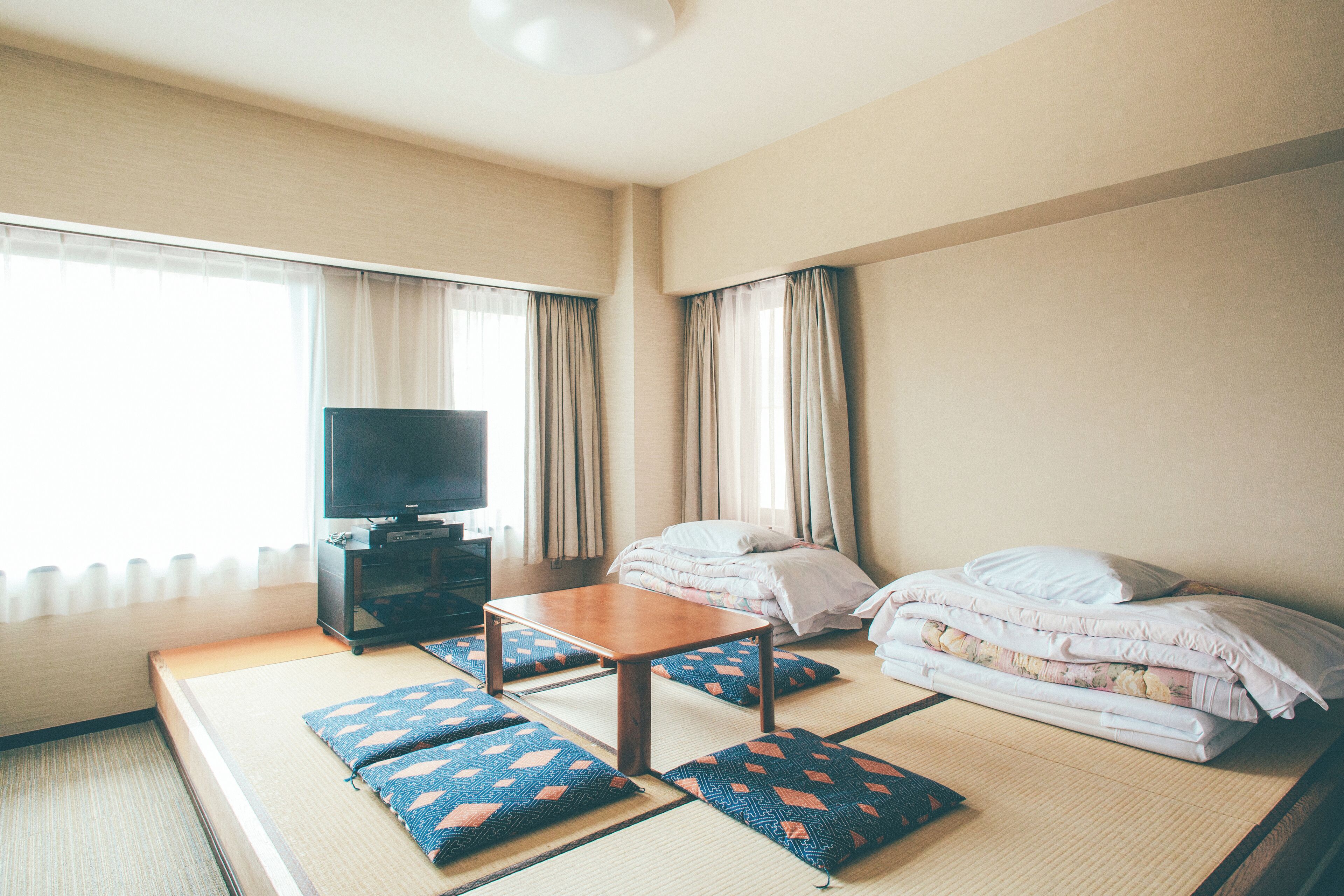 Ein Hotelzimmer mit Bett, Fernseher auf einem Schrank, einem kleinen Tisch und einer Couch.