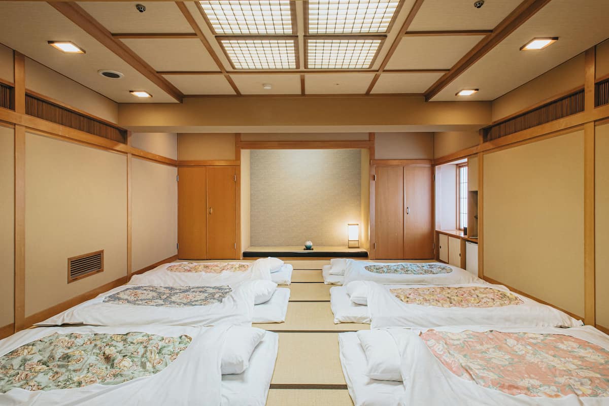 A traditional Japanese-style room with tatami flooring, wooden sliding doors, and a central tatami mat arrangement.