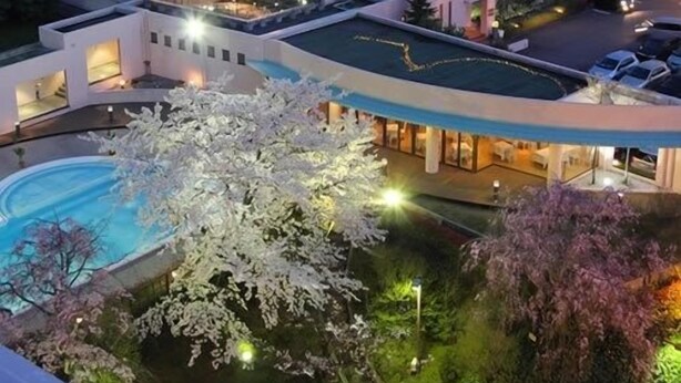 A modern hotel with multiple buildings, a swimming pool, and well-lit outdoor areas.