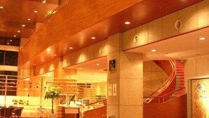 A spacious lobby with a wooden ceiling, a spiral staircase, and a reception desk.