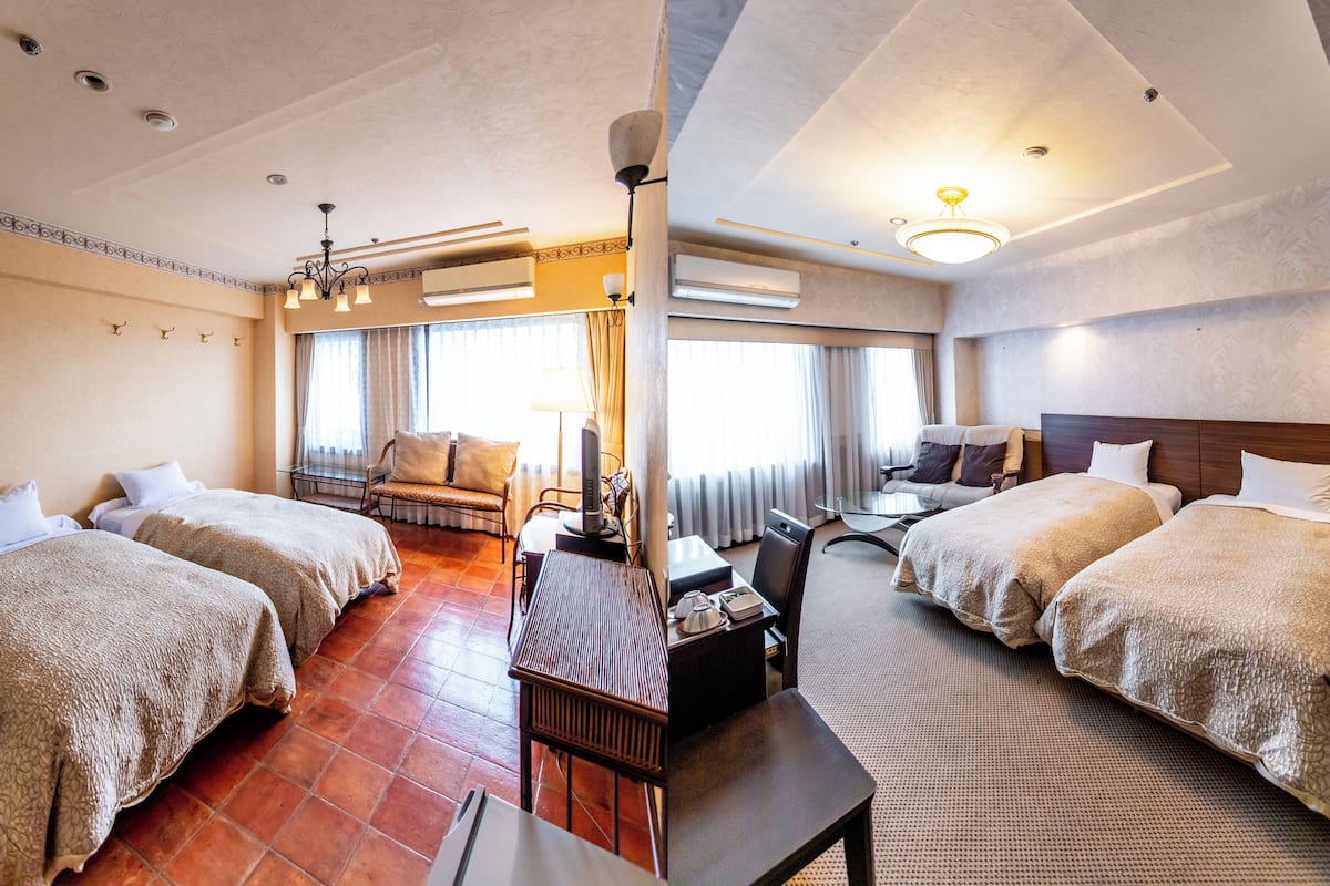 A hotel room with two beds, a desk, a chair, a TV, and a window with curtains.