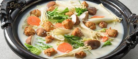 A traditional soup with various ingredients in a black ceramic bowl.