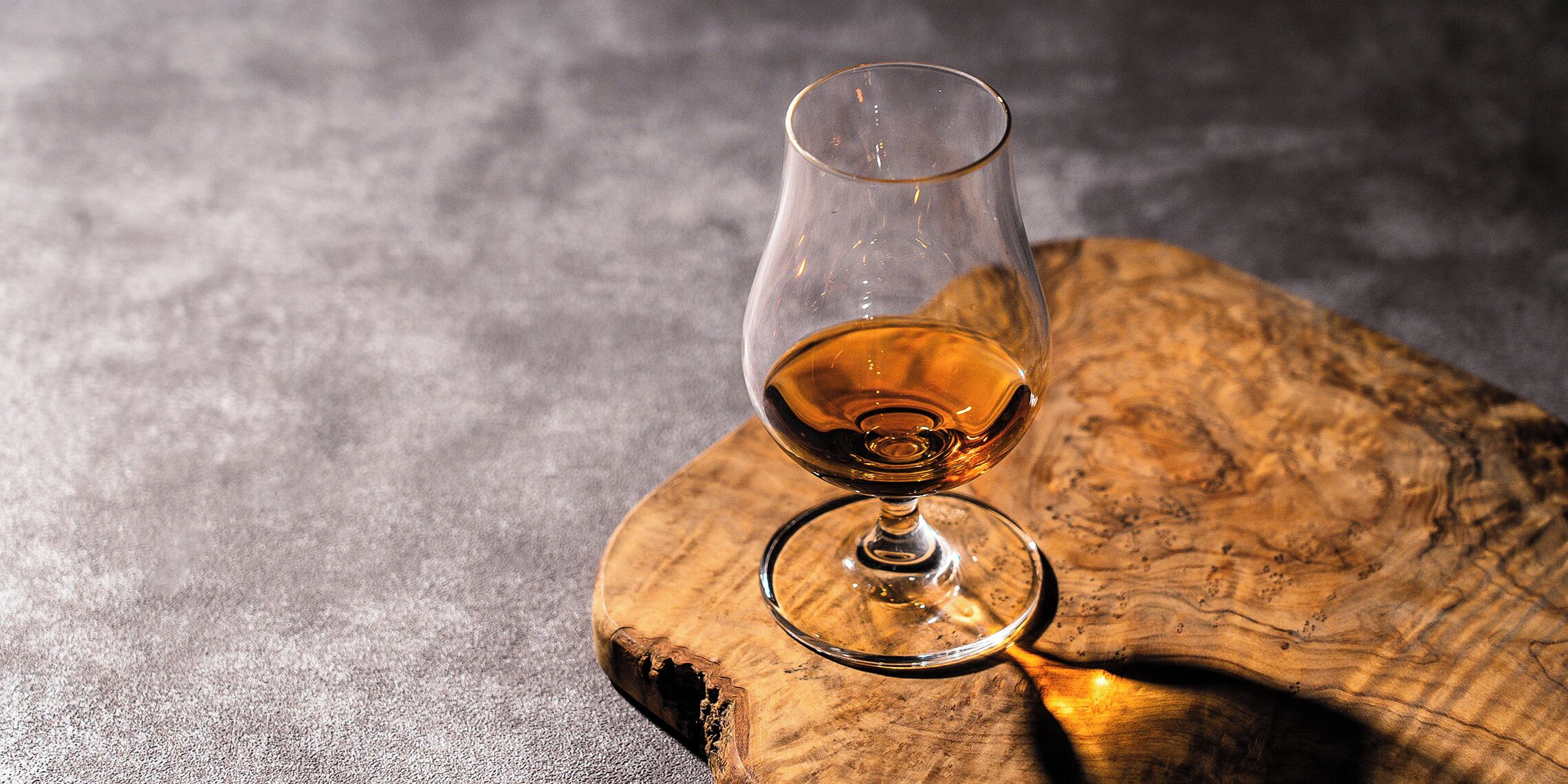 A glass of amber liquid on a wooden surface.