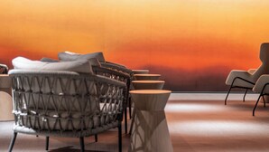 A modern lounge area with a curved seating arrangement, a wooden coffee table, and a large wall with a gradient color scheme. - Grand Mercure Nara Kashihara (Kashihara)