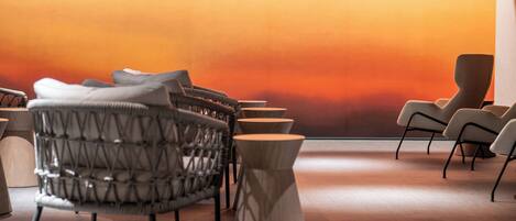 A modern lounge area with a curved seating arrangement, a wooden coffee table, and a large wall with a gradient color scheme.