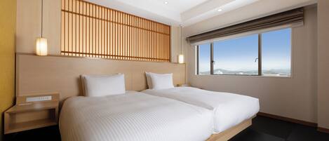 A modern hotel room with a large bed, a wooden headboard, a nightstand, and a window with a city view.