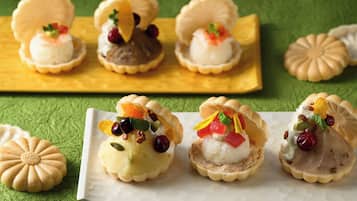 Diversos postres en recipientes con forma de concha, algunos con frutas y frutos secos, sobre una superficie verde con textura.