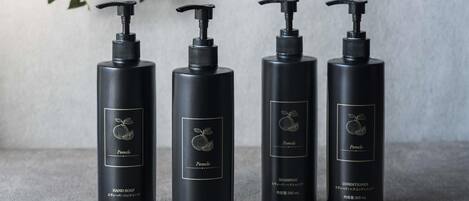 Four black bottles with pump dispensers, each labeled with 'Pomelo' and different product types.