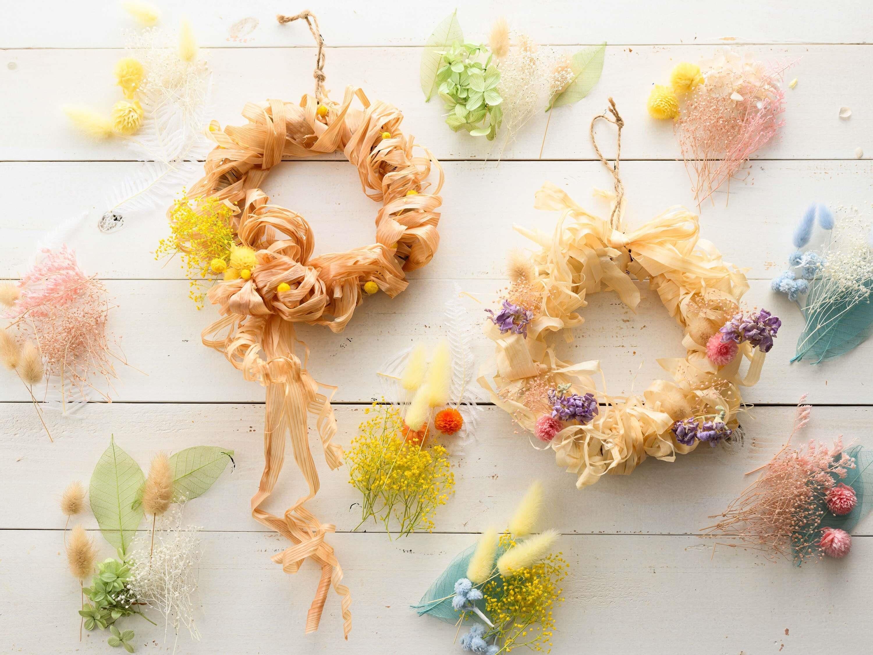 Two heart-shaped wreaths on a wooden surface with various flowers and greenery.