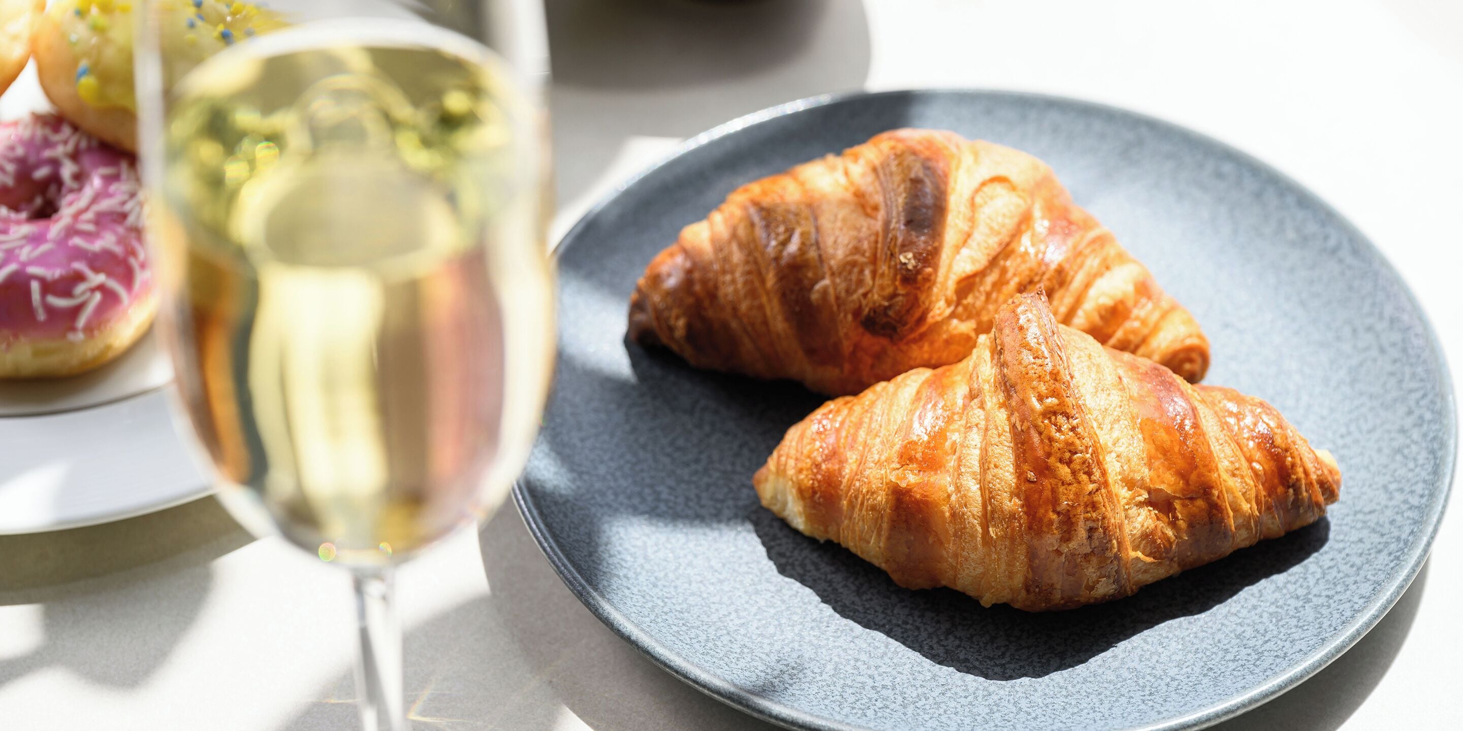Ein Teller mit zwei Croissants und einem Glas Weißwein.