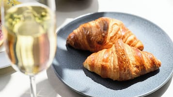 Ein Teller mit zwei Croissants und einem Glas Weißwein.