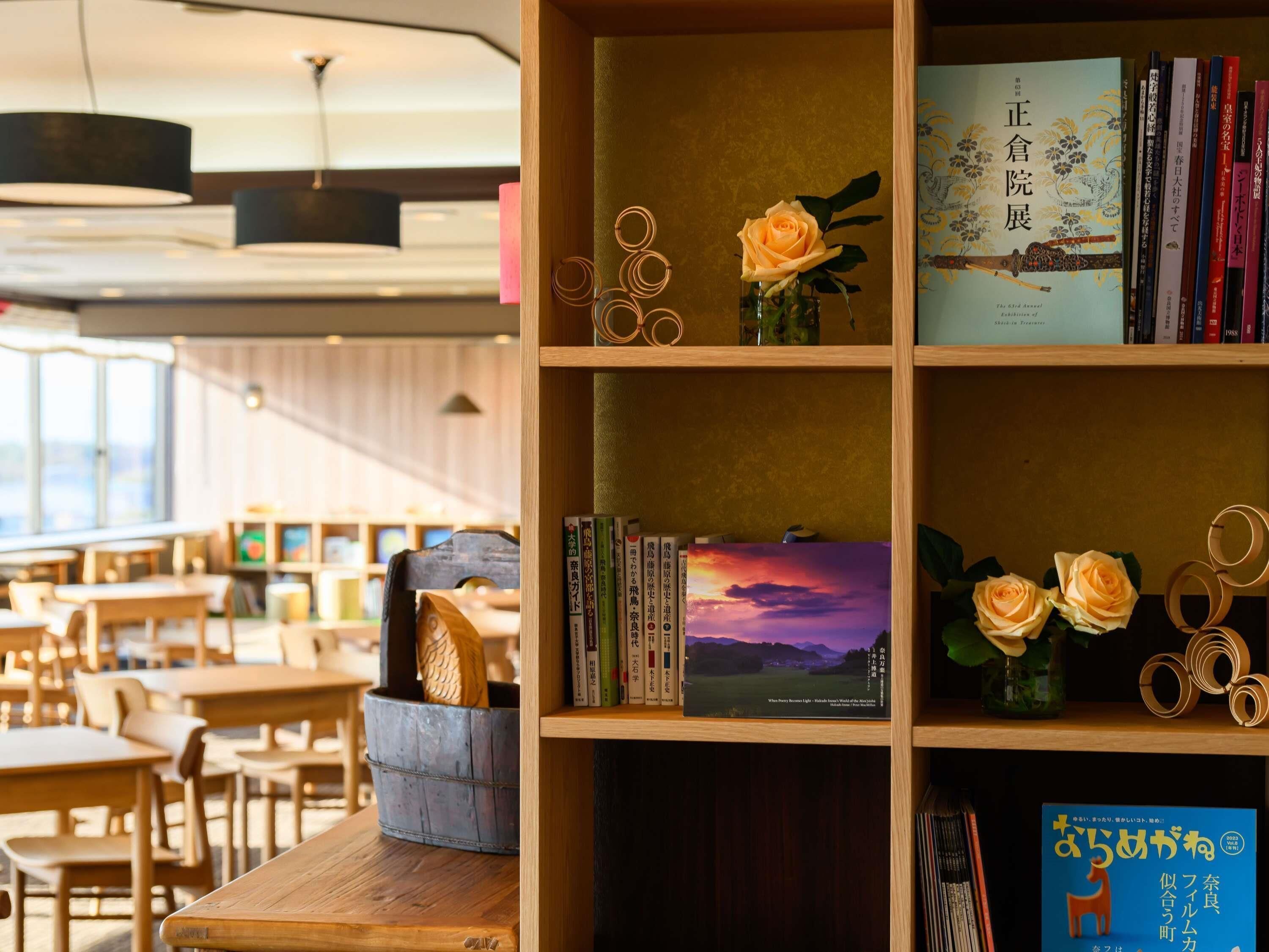 A library with bookshelves, a wooden table, and a vase with roses.